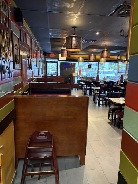 This restaurant interior features wooden booths, pendant lighting, and a dining area with tables — MIAMI, FL