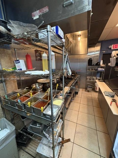 A commercial kitchen features stainless steel equipment, metal shelving units, and tiled flooring — MIAMI, FL