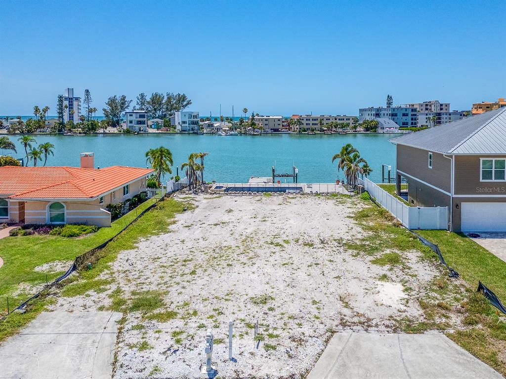 A vacant waterfront lot features a swimming pool and dock overlooking a bay — 10126 TARPON DRIVE, TREASURE ISLAND, FL