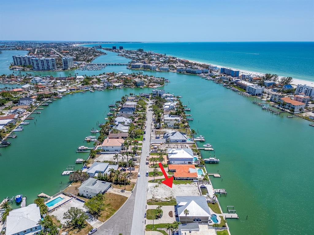 An aerial view shows a vacant waterfront lot situated between two houses on a canal — 10126 TARPON DRIVE, TREASURE ISLAND, FL