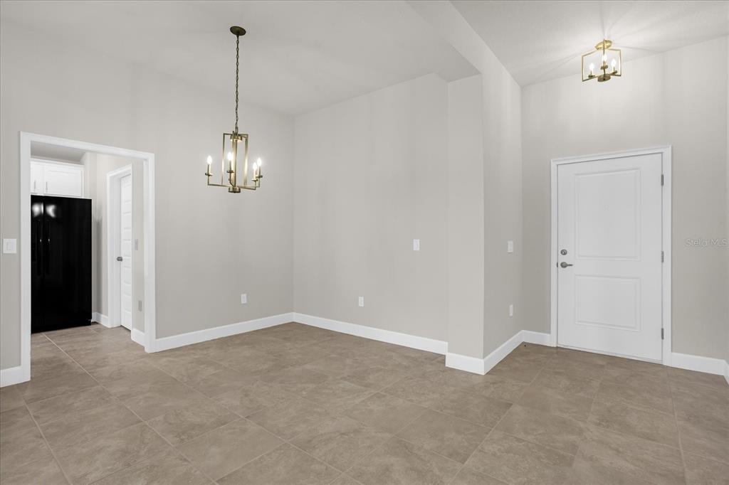 An empty dining area features light gray walls, tile flooring, and a hanging chandelier — 671 TANARO LANE, HAINES CITY, FL