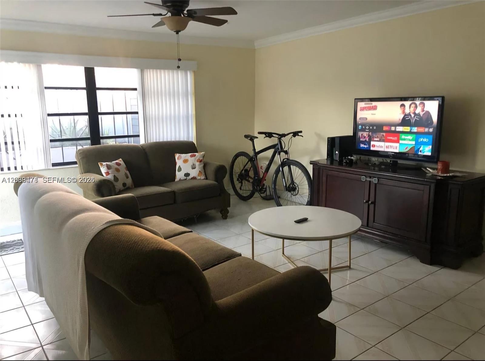 A living room features two brown sofas, a round coffee table, and a bicycle — 5813 SW 140th Ave # 5813, Miami FL 33183, MIAMI, FL