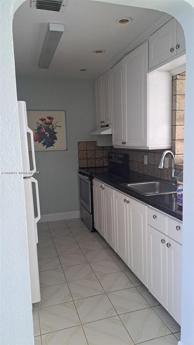 A galley kitchen features white cabinets, dark countertops, a stainless steel sink, and tiled flooring — 5813 SW 140th Ave # 5813, Miami FL 33183, MIAMI, FL