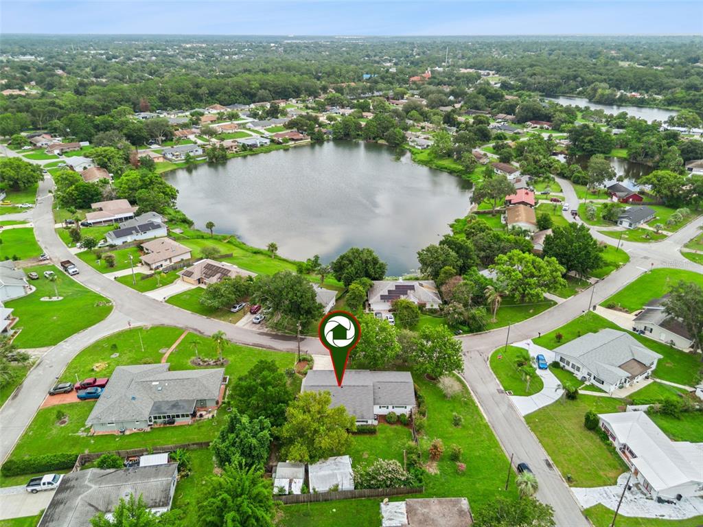 An aerial view shows a single-story house with a gray roof near a lake — 31 JASMINE DRIVE, DEBARY, FL
