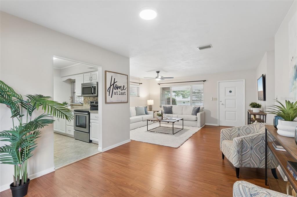 A living room with wood flooring opens to a kitchen with white cabinets and appliances — 31 JASMINE DRIVE, DEBARY, FL