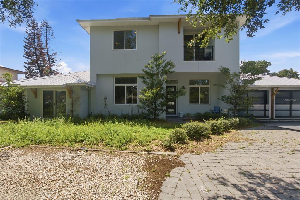 A two-story house with a light-colored exterior, metal roof, and a paved driveway — 281 BREWER AVENUE, WINTER PARK, FL