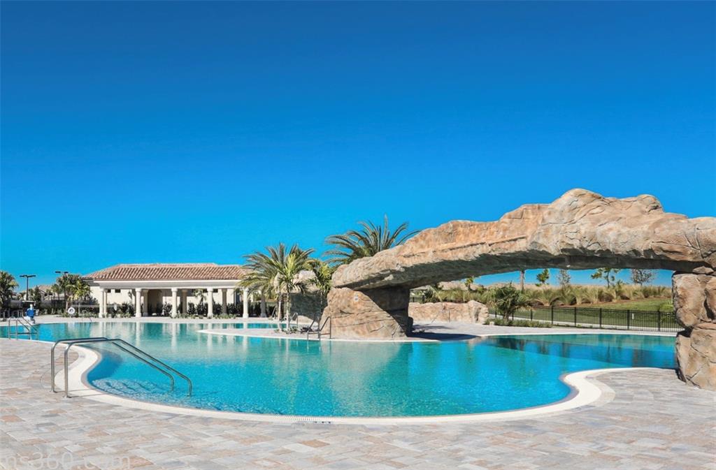 A swimming pool features a large rock-like archway structure and a nearby covered patio area — 16814 VARDON TERRACE UNIT 201, BRADENTON, FL