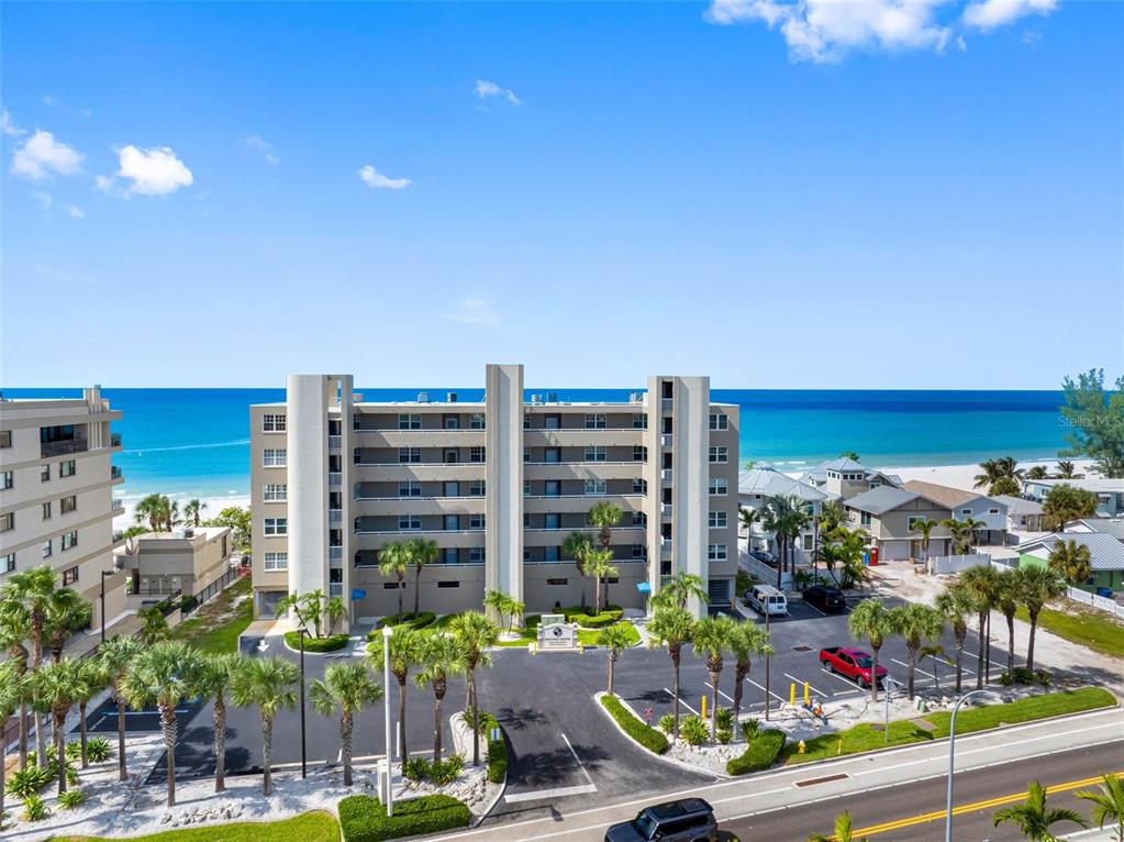 An open-concept living and dining area features wood-look flooring, a white sectional, and ocean views — 19710 GULF BOULEVARD UNIT 301, INDIAN SHORES, FL