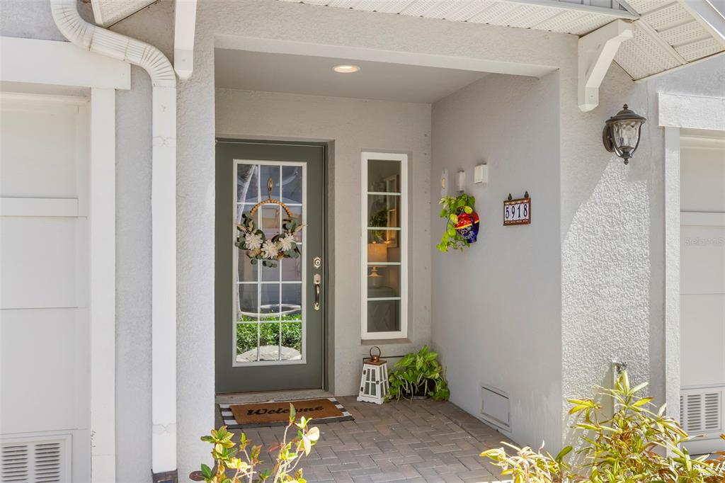 A front entryway features a gray door with a wreath, a side window, and plants — 5918 ANCHORAGE WAY S, ST PETERSBURG, FL