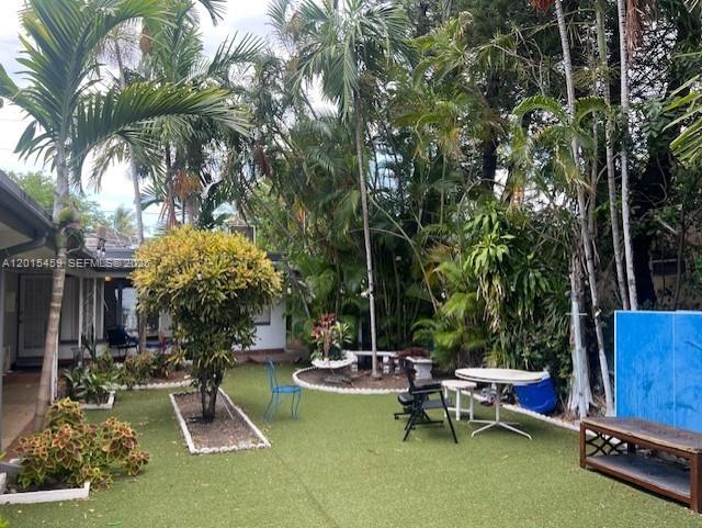A backyard with artificial turf, palm trees, a patio table, and a blue privacy screen — 732 Moffett # 4A, Hallandale Beach FL 33009, HALLANDALE BEACH, FL
