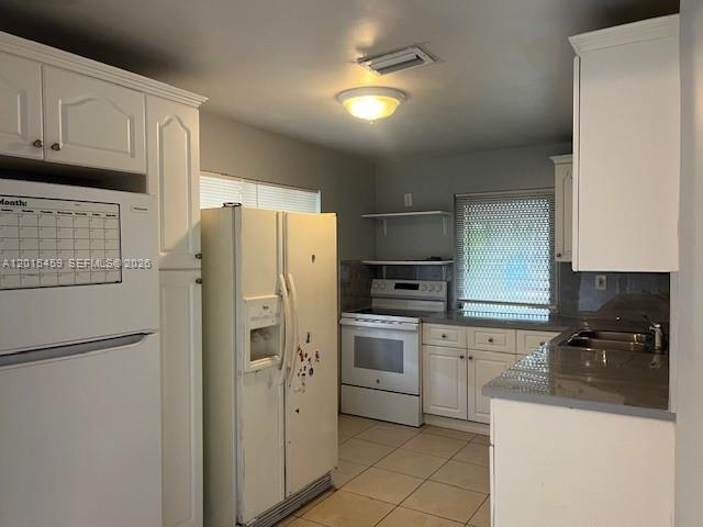 A kitchen features white cabinets, white appliances, a tiled floor, and a window with blinds — 732 Moffett # 4A, Hallandale Beach FL 33009, HALLANDALE BEACH, FL