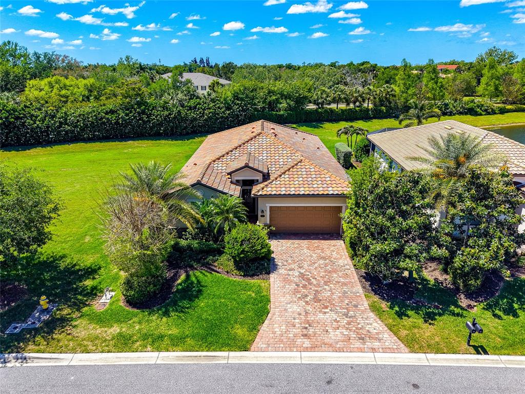 An aerial view of a single-story house with a tiled roof and brick driveway — 157 WANDERING WETLANDS CIRCLE, BRADENTON, FL