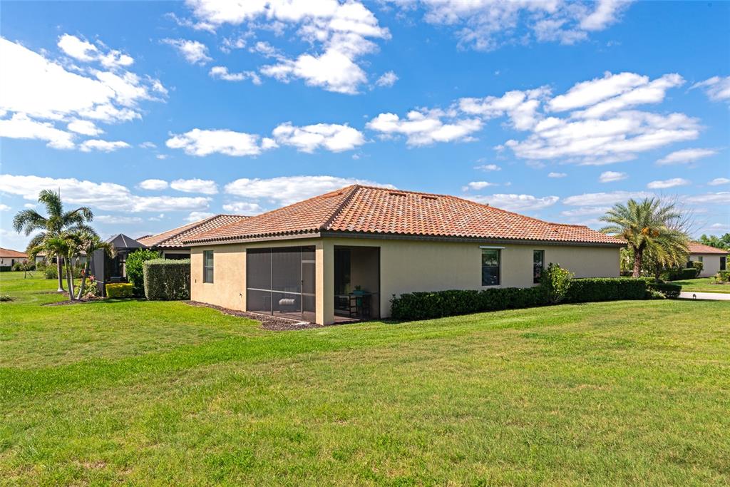 The exterior of a tan house with a tiled roof and a screened-in patio — 157 WANDERING WETLANDS CIRCLE, BRADENTON, FL