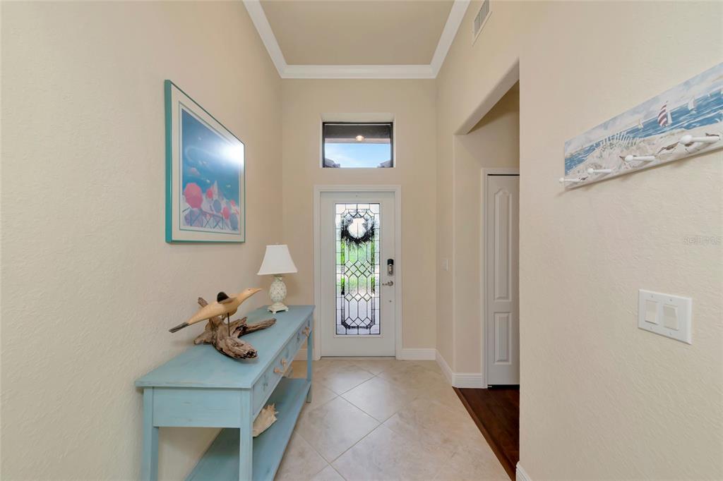 An entryway features a light blue console table, tiled floors, and a glass-paneled front door — 157 WANDERING WETLANDS CIRCLE, BRADENTON, FL