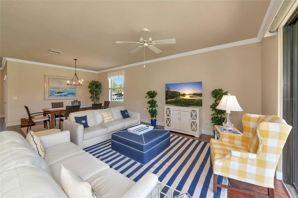 A living room features a white sofa, a blue ottoman, and a yellow plaid armchair — 157 WANDERING WETLANDS CIRCLE, BRADENTON, FL