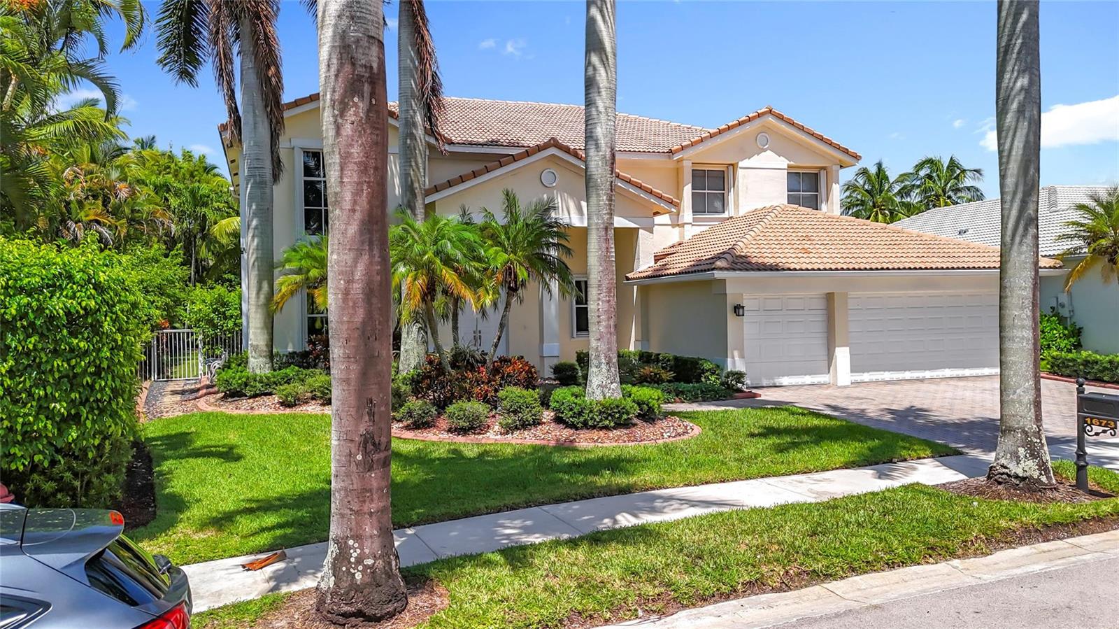 A two-story house with a tiled roof, palm trees, and a two-car garage — 1673 Victoria Pointe Circle, Weston FL 33327, WESTON, FL