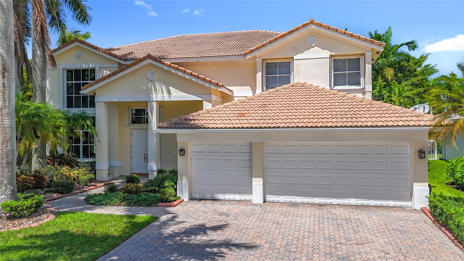 A two-story house with a beige stucco exterior, tile roof, and a two-car garage — 1673 Victoria Pointe Circle, Weston FL 33327, WESTON, FL