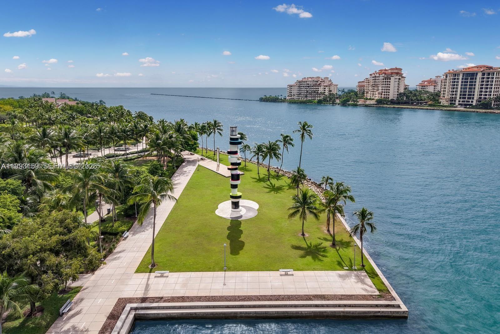 An aerial view of a waterfront park featuring a tall, striped sculpture on a lawn — 300 S Pointe Drive # 801, Miami Beach FL 33139, MIAMI BEACH, FL