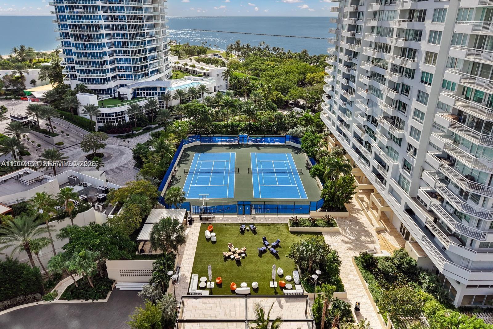 An aerial view shows two tennis courts and a grassy courtyard between two high-rise buildings — 300 S Pointe Drive # 801, Miami Beach FL 33139, MIAMI BEACH, FL