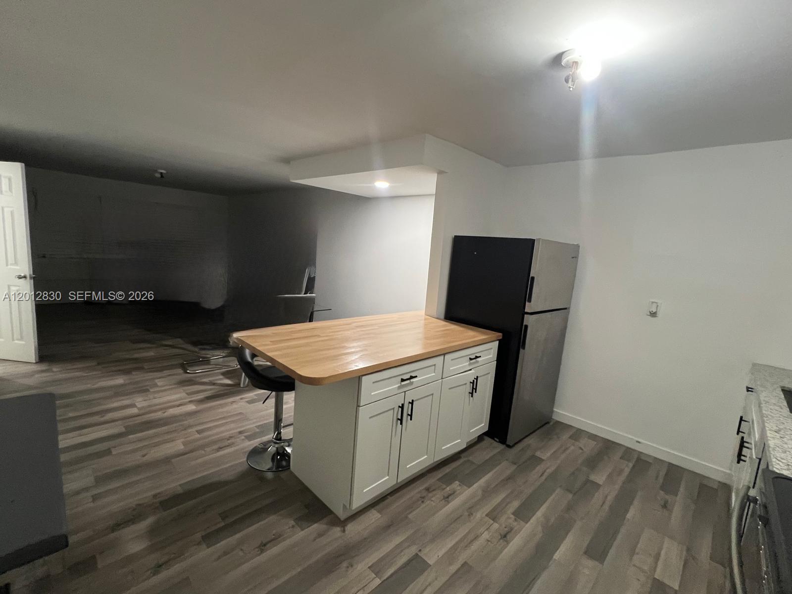 A kitchen area features a white island with a wood countertop and a stainless refrigerator — 1560 NE 151st St # 102, Miami FL 33162, MIAMI, FL
