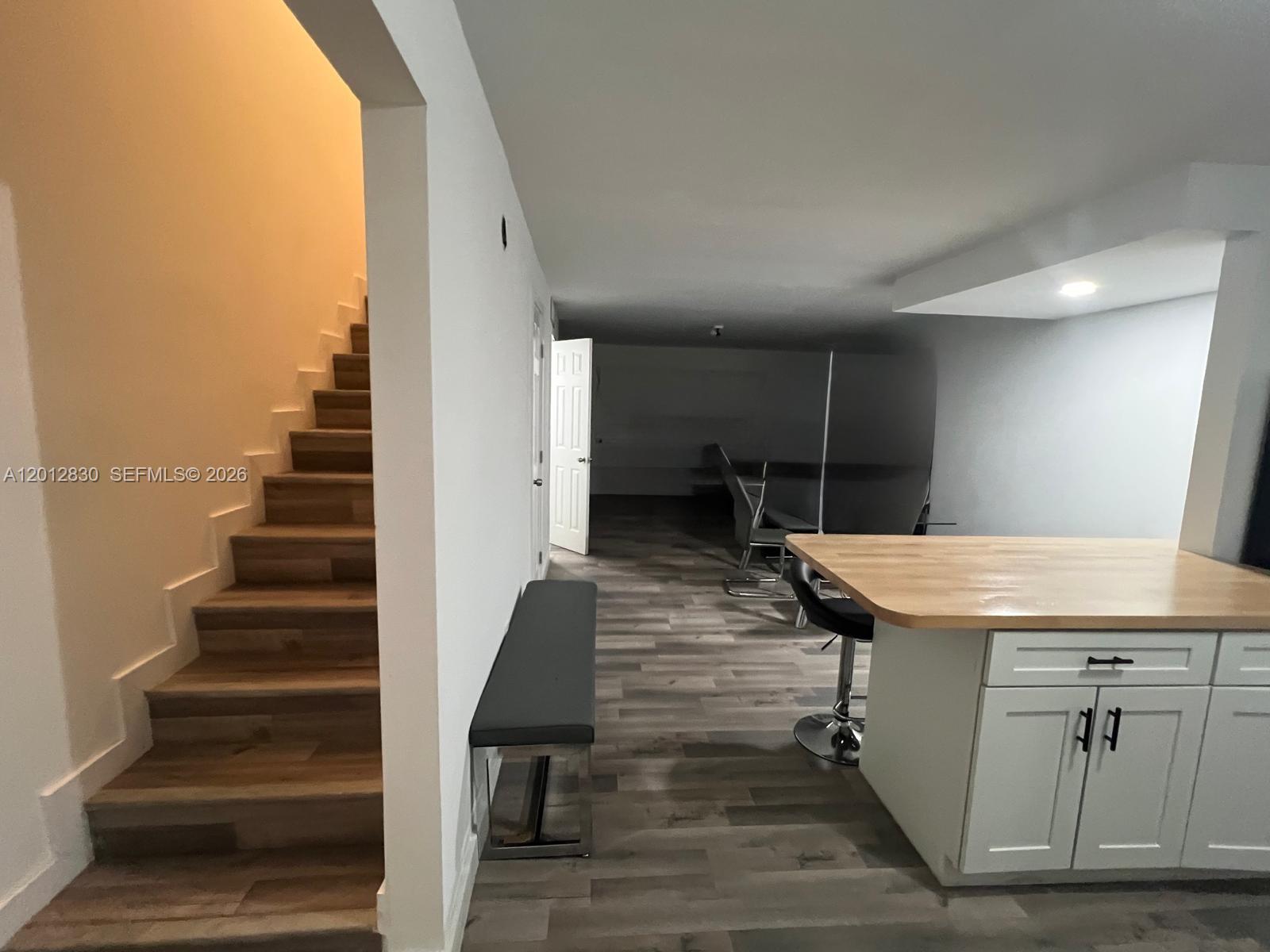 A room features a wooden staircase, a kitchen island with a wood top, and flooring — 1560 NE 151st St # 102, Miami FL 33162, MIAMI, FL