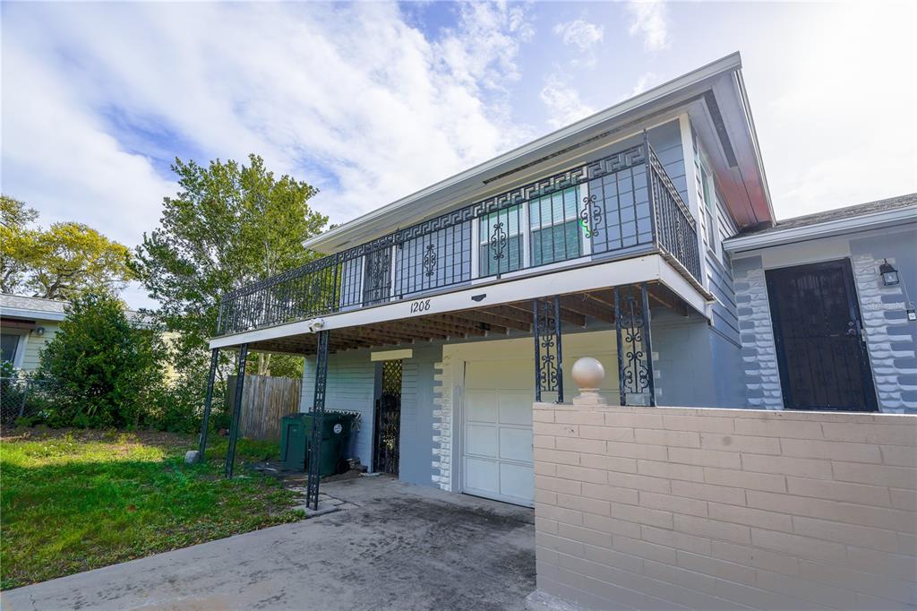 A two-story house features a second-floor balcony with decorative iron railings above a garage — 1208 N HALIFAX AVENUE, DAYTONA BEACH, FL