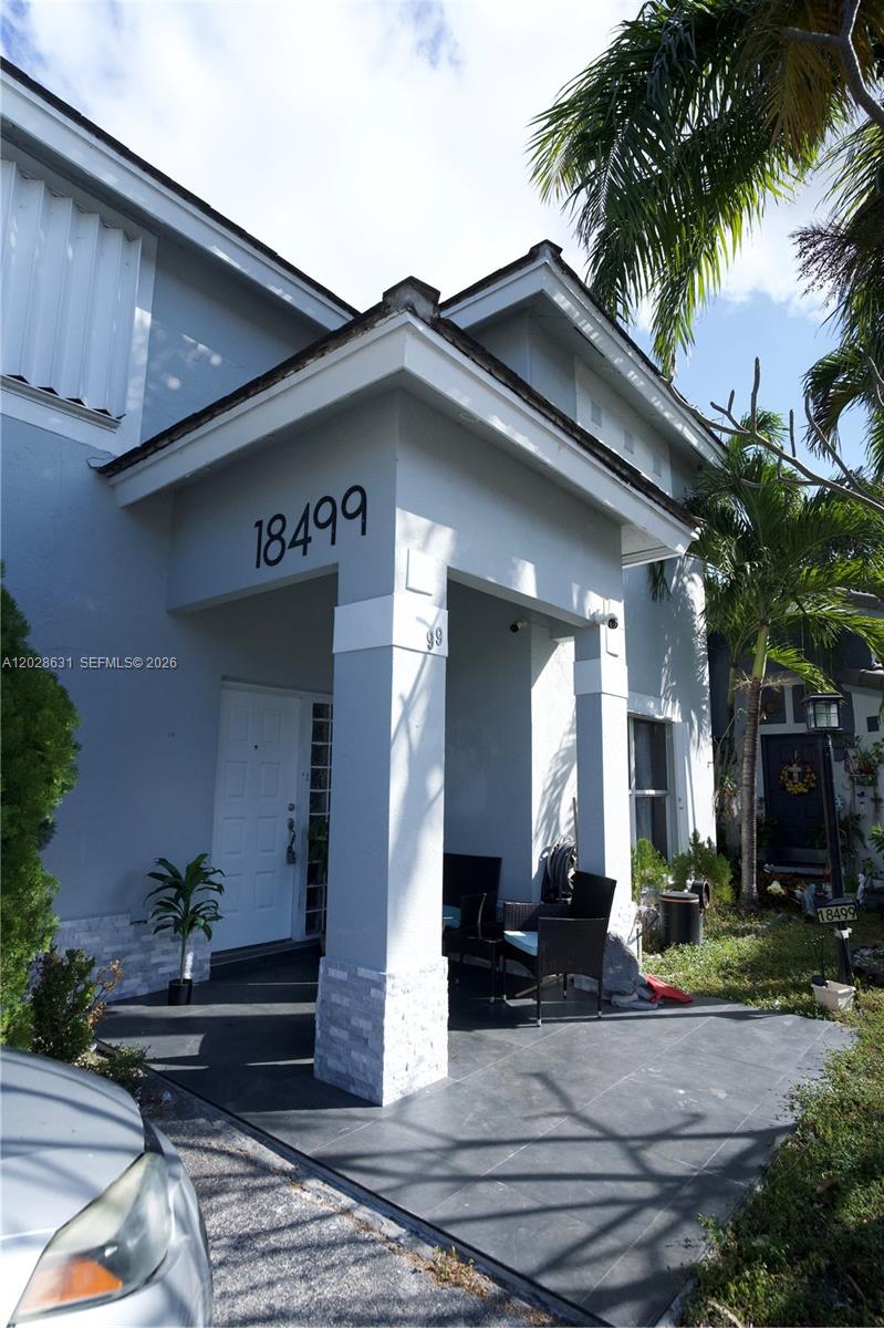 A light gray house exterior features a covered front porch with dark tiled flooring — 18499 NW 52nd Path, Miami Gardens FL 33055, MIAMI GARDENS, FL