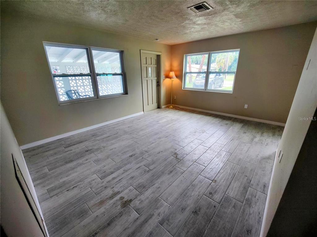 An empty room features light-colored wood-look tile flooring, two windows, and a central door — 190 DANFORTH DRIVE, PUNTA GORDA, FL