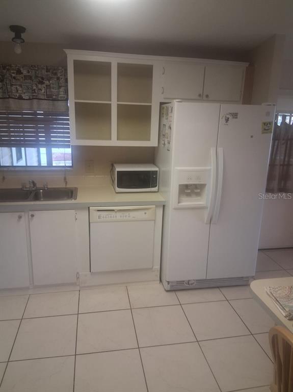 A kitchen features white cabinets, a white refrigerator, a dishwasher, and a double sink — 1550 HILLCREST DRIVE, THE VILLAGES, FL