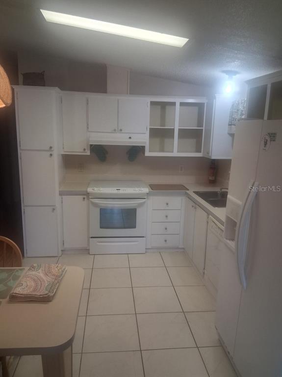 A kitchen with white cabinets, white appliances, and light-colored tile flooring — 1550 HILLCREST DRIVE, THE VILLAGES, FL