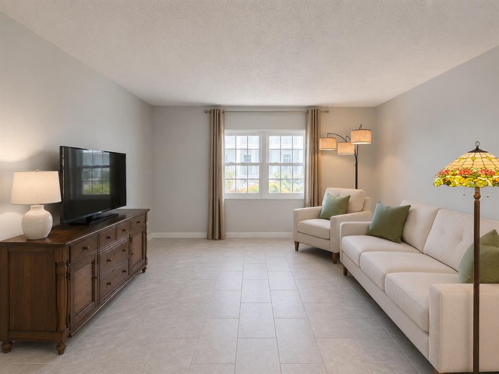 A living room features light tile flooring, a wooden media console, and neutral-toned seating — 1706 BELLEAIR FOREST DRIVE UNIT 244, BELLEAIR, FL