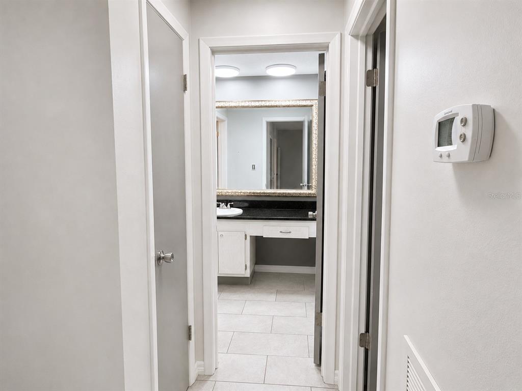 A hallway leads to a bathroom featuring a vanity with a dark countertop and mirror — 1706 BELLEAIR FOREST DRIVE UNIT 244, BELLEAIR, FL