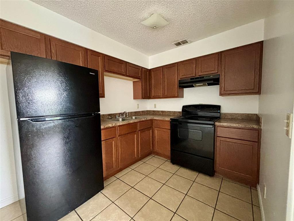 A kitchen features wood cabinets, black appliances, tile flooring, and laminate countertops — 503 N LANIER AVENUE, FORT MEADE, FL