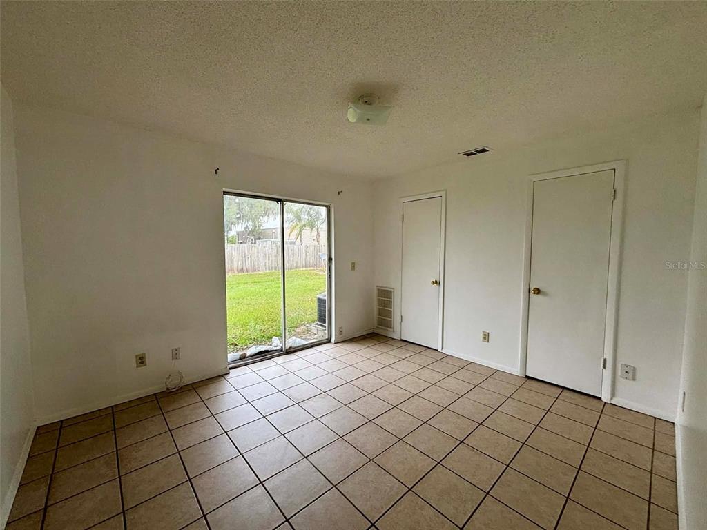 An empty room with beige tile flooring, two white doors, and a sliding glass door — 503 N LANIER AVENUE, FORT MEADE, FL