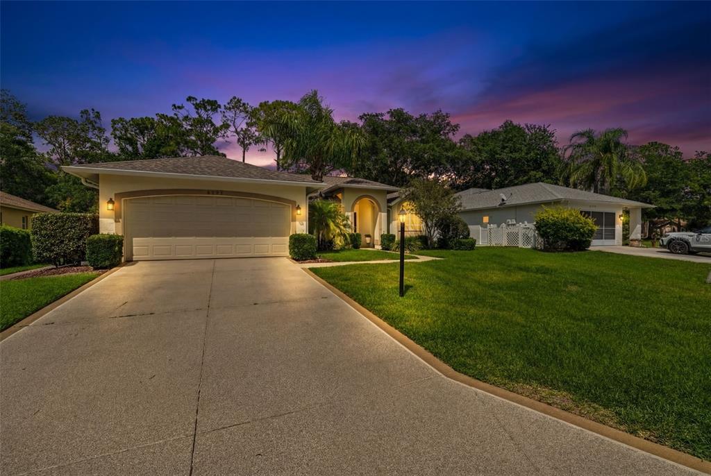 A single-story house with a two-car garage and a concrete driveway at dusk — 2593 CRYSTAL LAKE DRIVE, SPRING HILL, FL