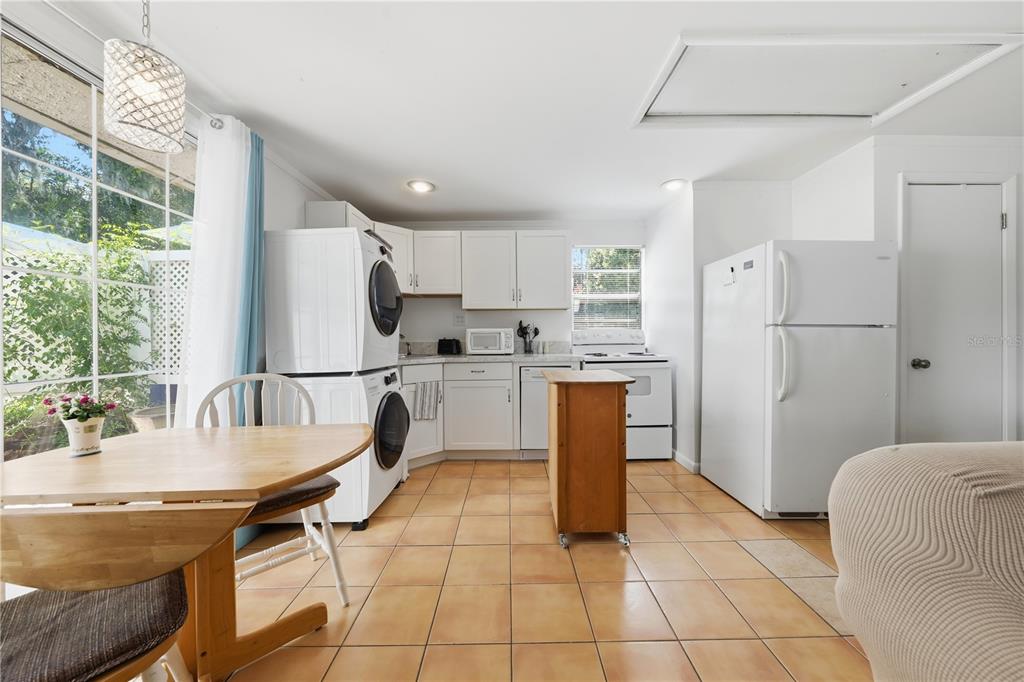 A kitchen with white cabinets, a stacked washer and dryer, and tan tile flooring — 206 E 9TH AVENUE, MOUNT DORA, FL