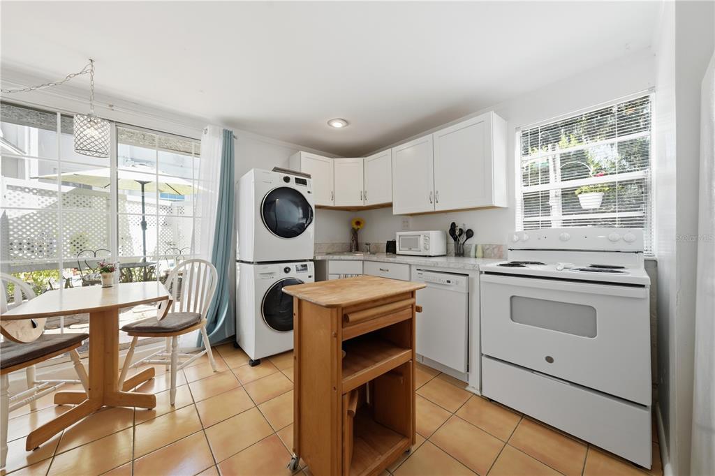 A kitchen with white cabinets, white appliances, a stacked washer-dryer, and a wooden island — 206 E 9TH AVENUE, MOUNT DORA, FL
