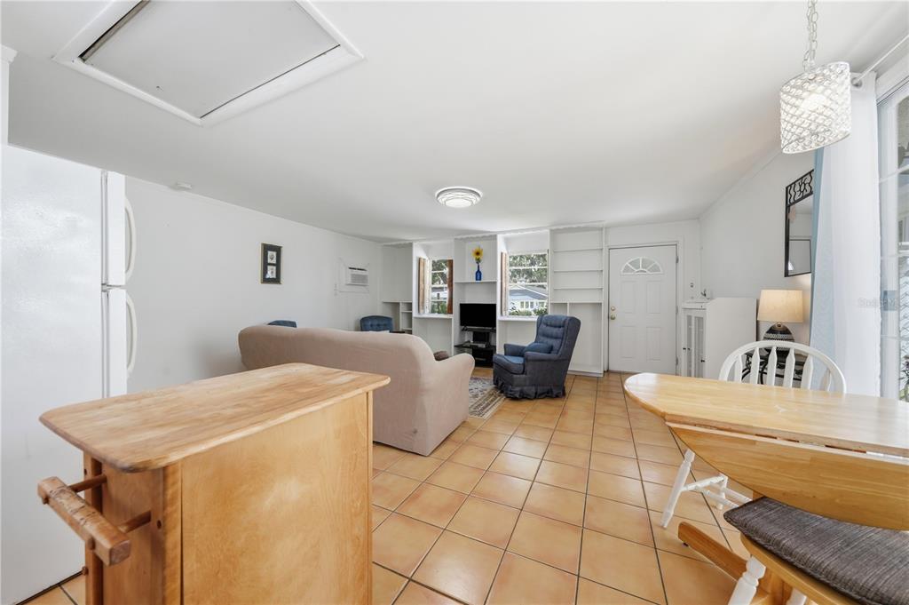 An open-concept living and dining area features tile flooring, built-in shelving, and a wooden island — 206 E 9TH AVENUE, MOUNT DORA, FL