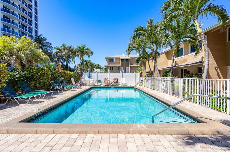 A rectangular swimming pool is surrounded by lounge chairs, palm trees, and residential buildings — 3409 SE 8th Street # 6, Pompano Beach FL 33062, POMPANO BEACH, FL