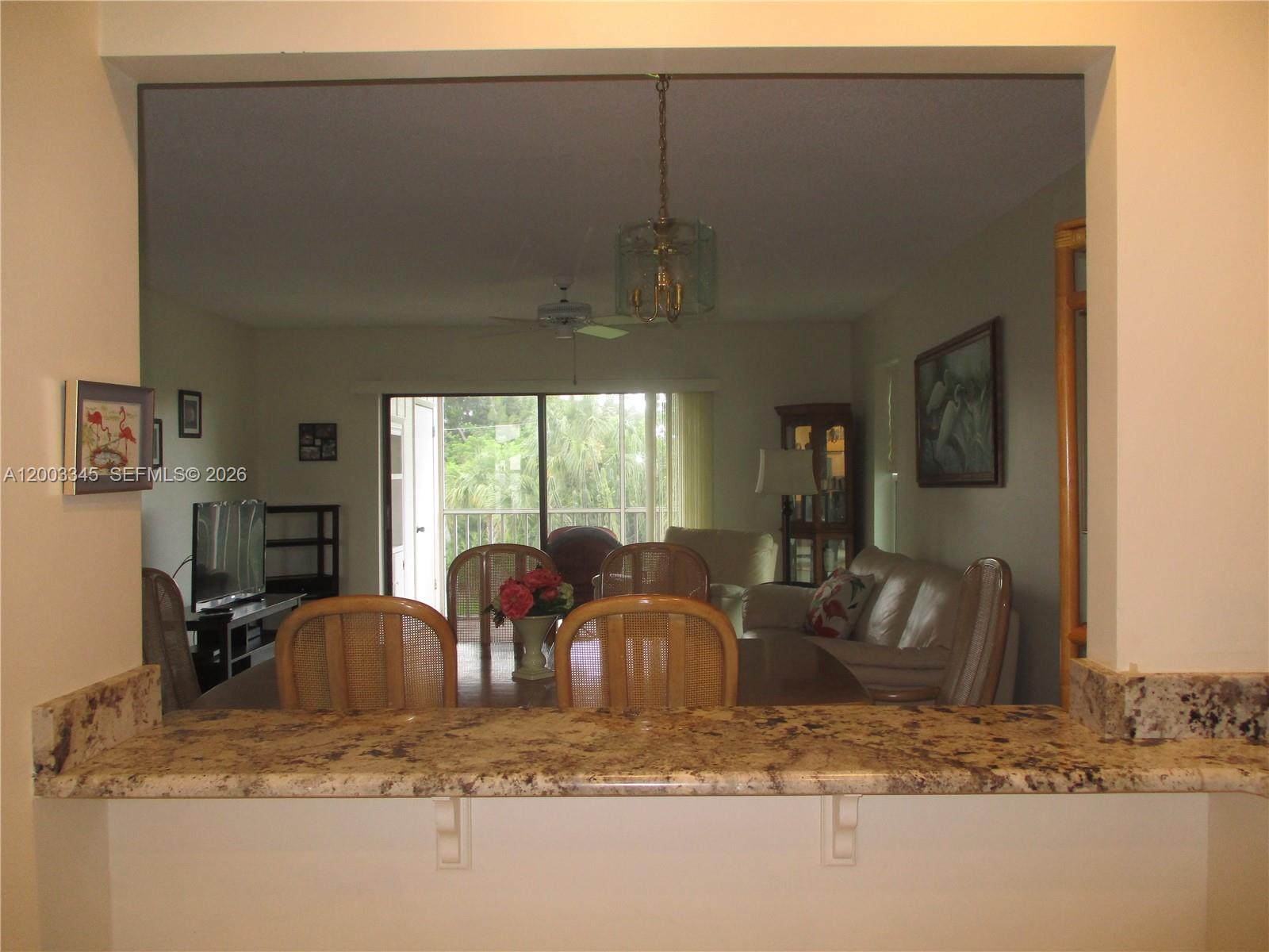 A granite breakfast bar overlooks a dining area and living room with a sliding glass door — 6531 SE Federal Hwy # S212, Stuart FL 34997, STUART, FL