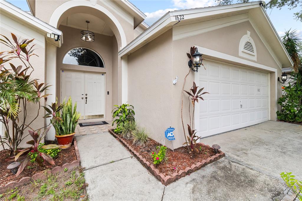 The exterior of a beige house features a double front door, a garage, and landscaping — 1622 HULETT DRIVE, BRANDON, FL