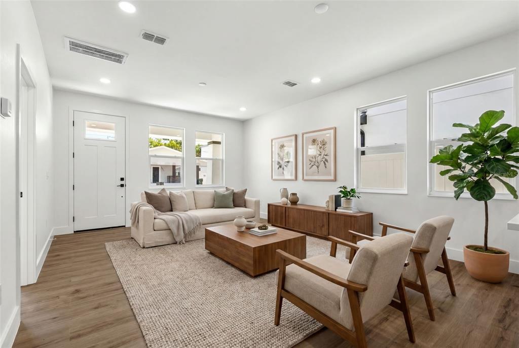 A bright living room features light wood floors, a beige sofa, and two wooden armchairs — 2912 N 21ST STREET, TAMPA, FL