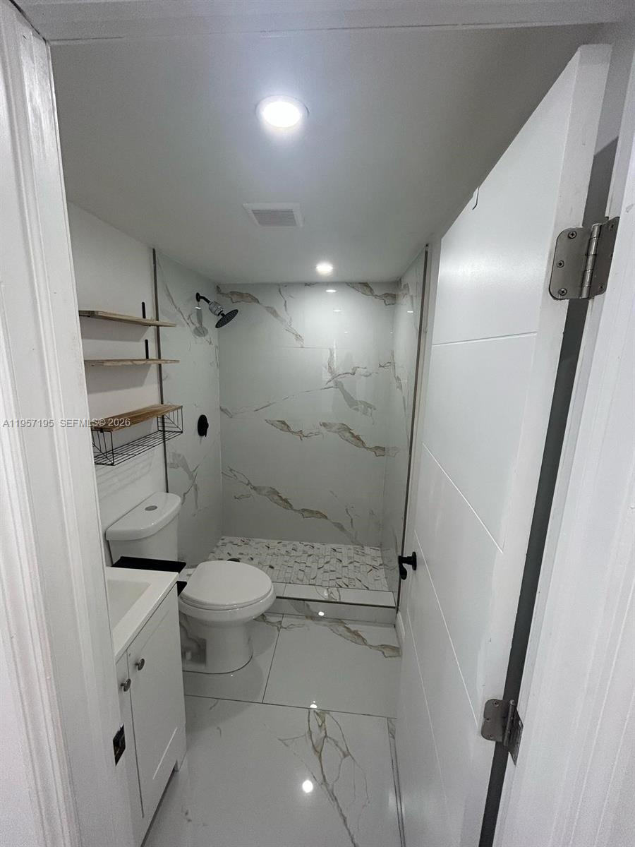 A small bathroom features a walk-in shower with marble-patterned tile and a white vanity — 2331 Coolidge St, Hollywood FL 33020, HOLLYWOOD, FL