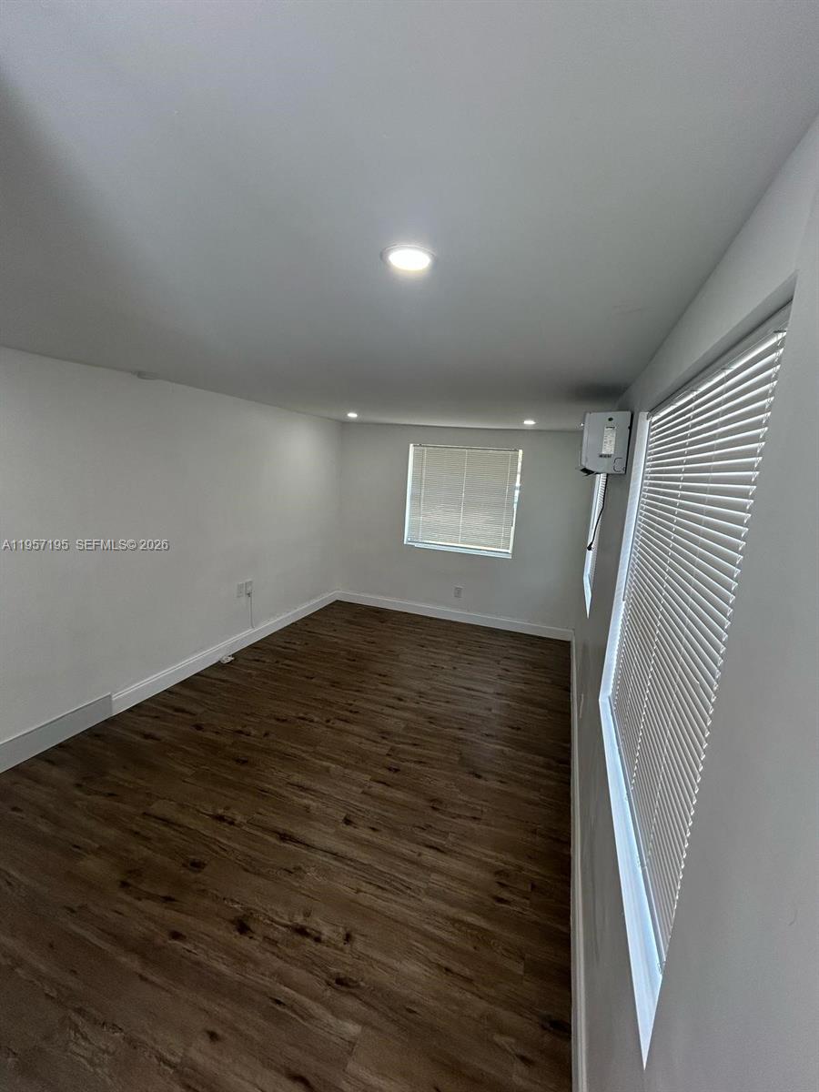 An empty room features white walls, recessed lighting, and dark wood-look flooring — 2331 Coolidge St, Hollywood FL 33020, HOLLYWOOD, FL