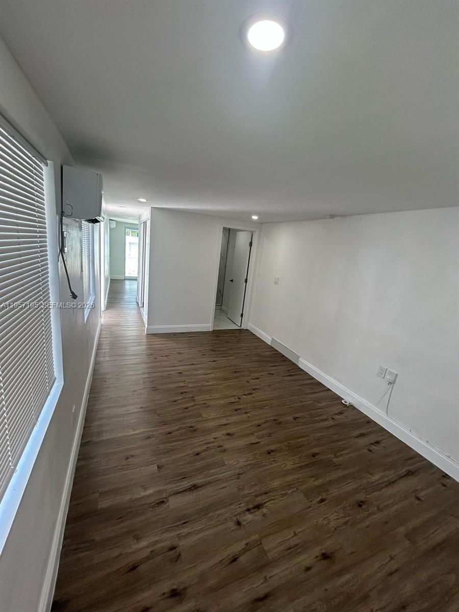 An empty room features wood-look flooring, white walls, recessed lighting, and a doorway leading to a hallway — 2331 Coolidge St, Hollywood FL 33020, HOLLYWOOD, FL