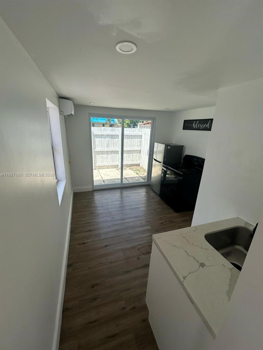 A small kitchen features white cabinets, a quartz countertop, and a sliding glass door — 2331 Coolidge St, Hollywood FL 33020, HOLLYWOOD, FL