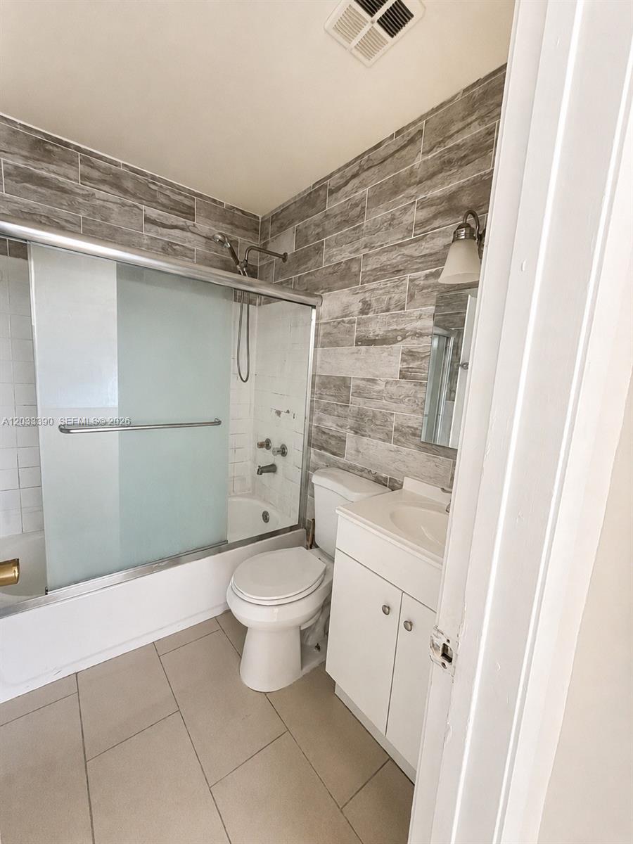 A bathroom features a tub-shower combo, a white vanity, and gray wood-look wall tiles — 8480 SW 154th Cir Ct # 924, Miami FL 33193, MIAMI, FL