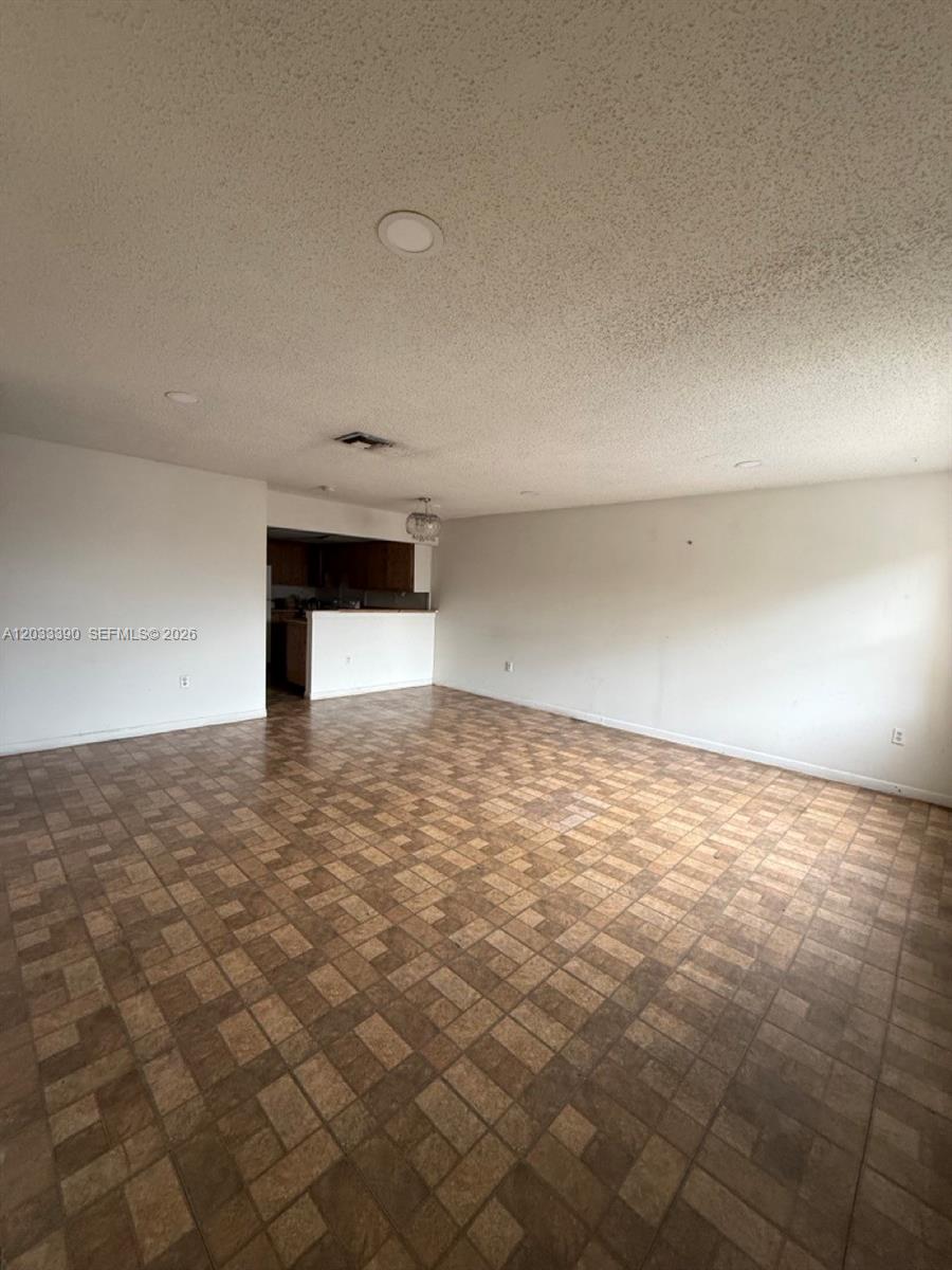 An empty room with tiled flooring, white walls, and recessed lighting leads toward a kitchen — 8480 SW 154th Cir Ct # 924, Miami FL 33193, MIAMI, FL