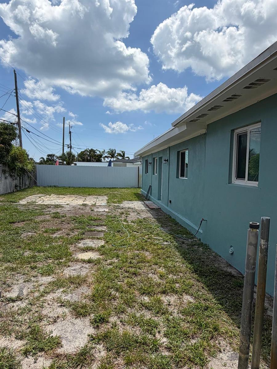 A side view of a teal house exterior with a grassy yard and white fence — 1405 6th Street, West Palm Beach FL 33401, WEST PALM BEACH, FL