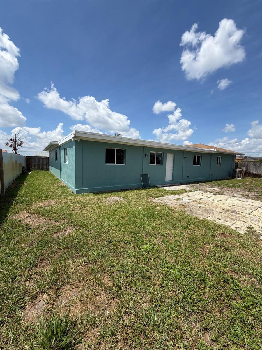 The exterior of a teal-colored house features a flat roof and a backyard lawn — 1405 6th Street, West Palm Beach FL 33401, WEST PALM BEACH, FL